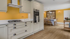 Une cuisine avec des meubles blancs, une cuisinière à gaz et un four.