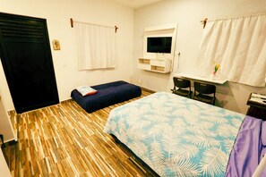 Ein Zimmer mit Bett, Schreibtisch, Fernseher und einem Fenster mit Vorhängen.