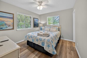A bedroom with a bed, a desk, and two windows with blinds. - Beach Access, Pool & Tennis - Sleeps 6 (Hilton Head Island)