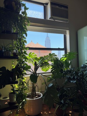 A room with a large window, potted plants, and an air conditioning unit. - Studio Loft in the heart of NYC  - 5 min walk to time square (New York)
