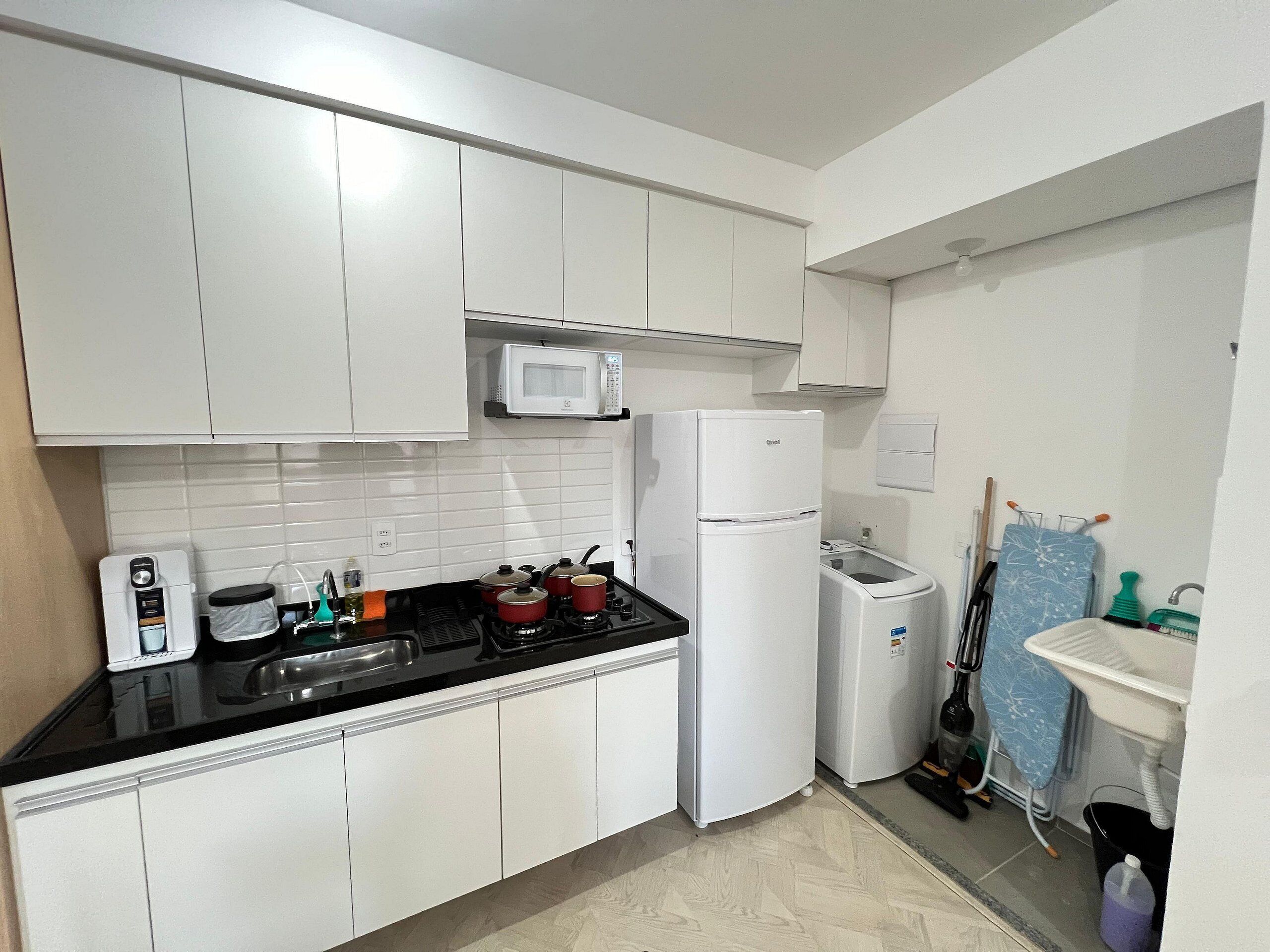 Una cocina con armarios blancos, un microondas, un refrigerador, una estufa y un lavamanos.