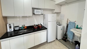 Una cocina con armarios blancos, un microondas, un refrigerador, una estufa y un lavamanos.