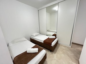 A hotel room with two beds, a large mirror, and a wardrobe.