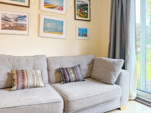 A living room with a grey sofa, two patterned cushions, and framed artwork on the wall. - NEW Family Home in Whitstable | Pets Welcome (Whitstable)