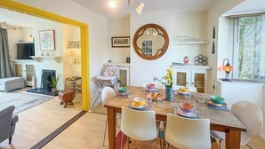 A dining area with a wooden table, white chairs, and a round mirror on the wall. - NEW Family Home in Whitstable | Pets Welcome (Whitstable)