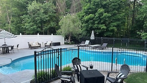 Ein Poolbereich mit umzäuntem Deck, Liegestühlen und einem Tisch.