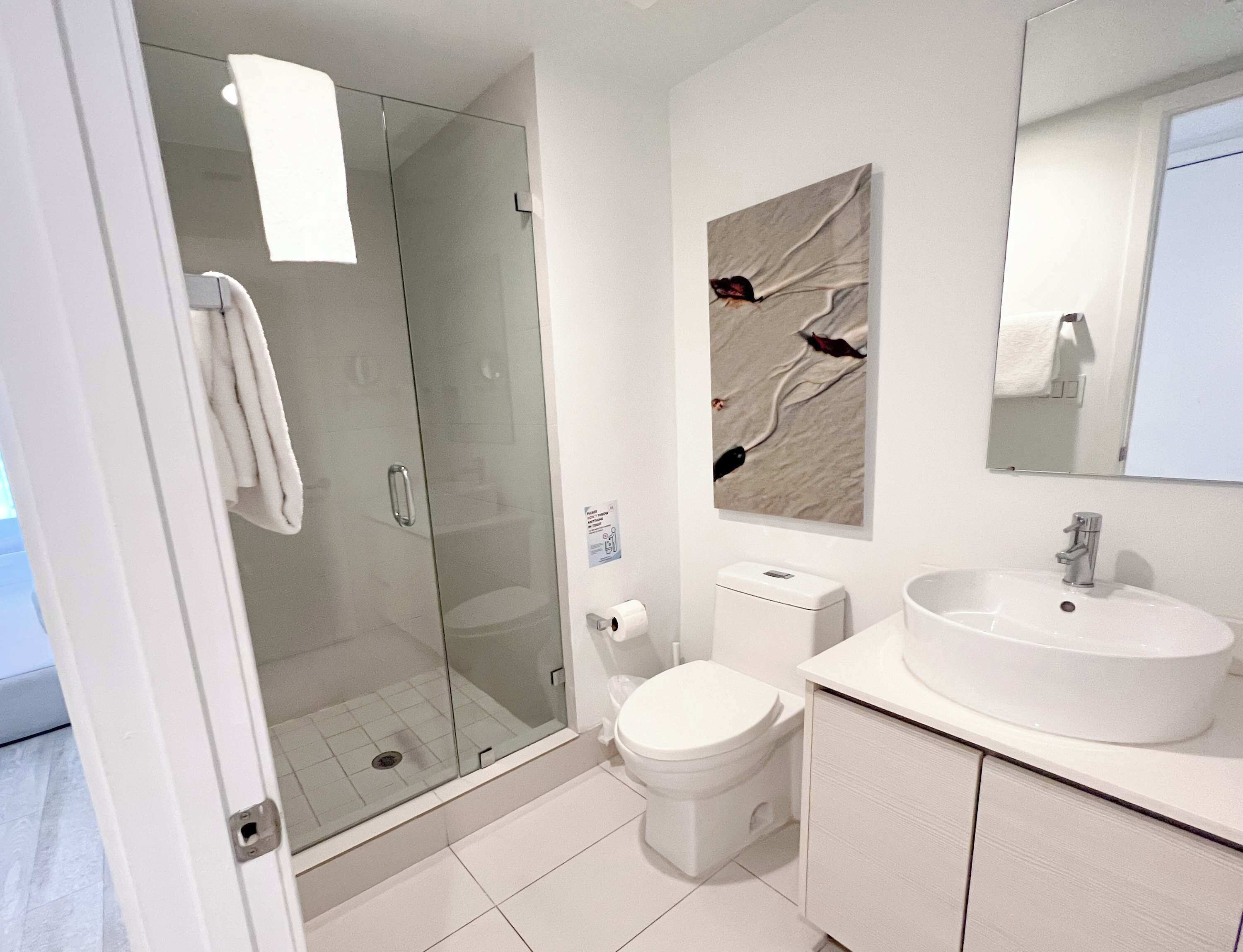 Un bagno moderno con cabina doccia in vetro, un water e un lavandino.