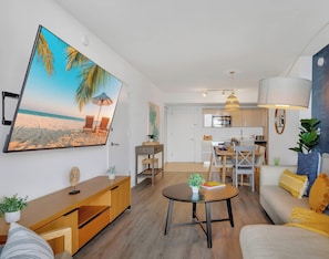 Ein modernes Wohnzimmer mit Essbereich, einer Küche und einem großen Wandbild zum Thema Strand.
