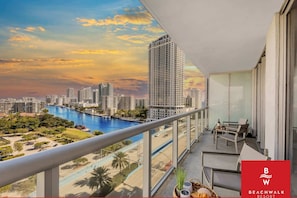 Ein Balkon mit Blick auf einen Stadtpanoramablick, ein Schwimmbad und einen Strand.