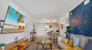 A modern living room with a large flat-screen TV, a dining area, and a kitchen. - Bright 2BR Condo · Intracoastal · Beachwalk (Hallandale Beach)
