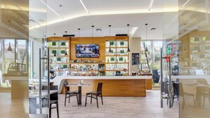 A modern bar area with a wooden counter, multiple seating options, and a television screen above the bar. - 1BR, Marina & Bay View, Resort & Beach (Hallandale Beach)
