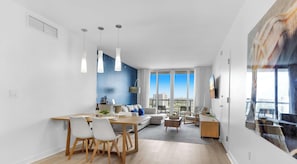 A modern apartment with a dining area, living space, and a balcony with a city view. - 1BR, Marina & Bay View, Resort & Beach (Hallandale Beach)