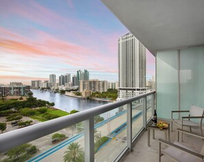 A balcony with a city view, a table with a bottle and fruit, and a chair. - Cozy Studio w/ Intracoastal View & Balcony (Hallandale Beach)