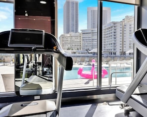 A gym with treadmills and a view of a pool and buildings. - Cozy Studio w/ Intracoastal View & Balcony (Hallandale Beach)
