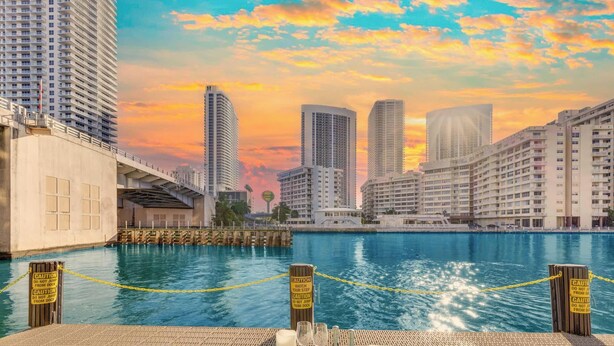 Zona de comedor frente al agua con vista al horizonte de la ciudad, un muelle y señales de precaución.