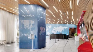 Un vestíbulo moderno con un mostrador de recepción, un quiosco informativo azul y un mapa del mundo en la pared.