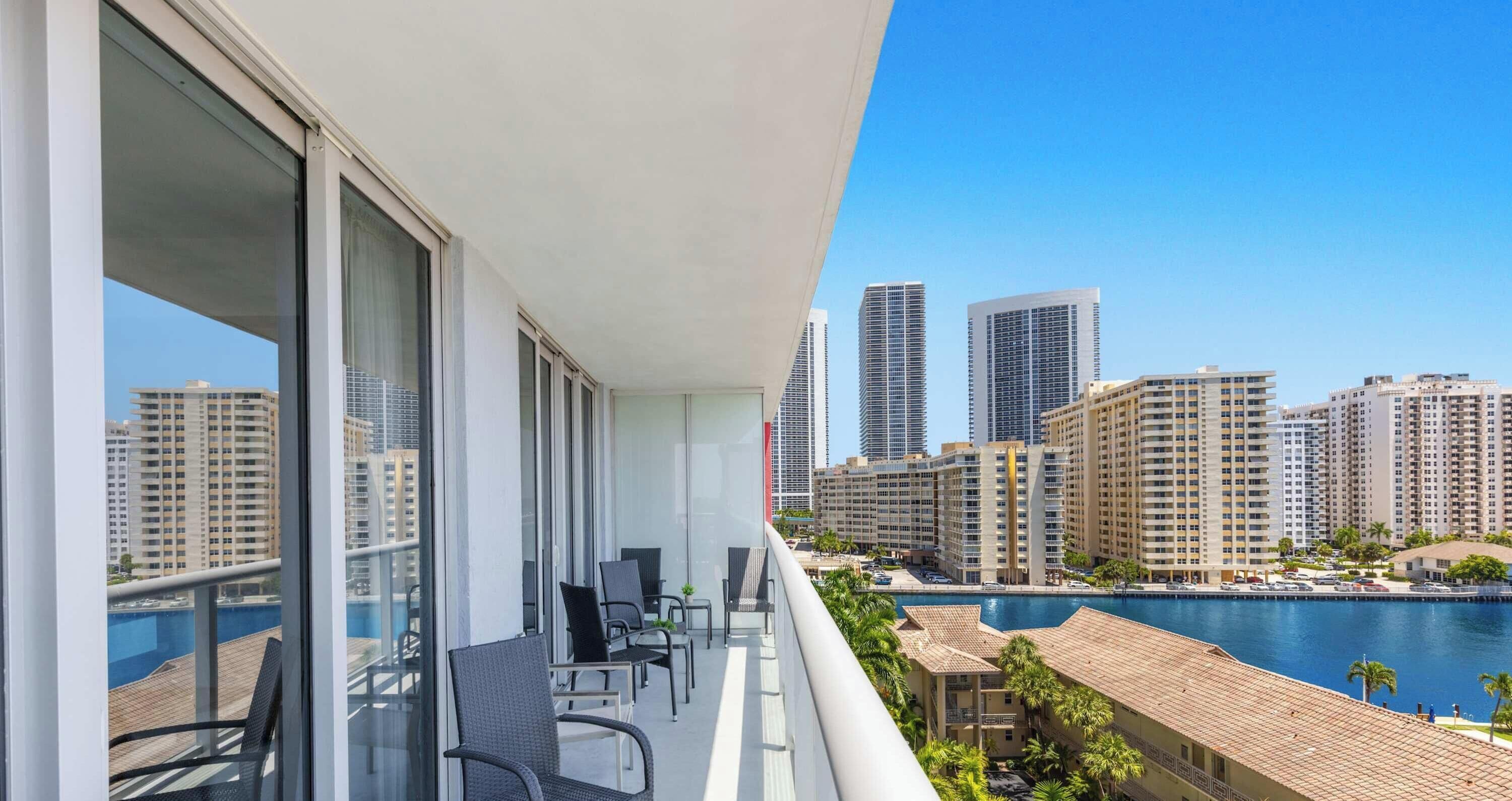 A balcony with a view of a city skyline and a pool.