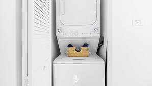 A white laundry machine with a basket of clothes on top. - 1BR · Sunset View · High Floor · W/D · Resort (Hallandale Beach)