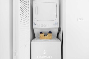 A white laundry machine with a basket of clothes on top. - 1BR · Sunset View · High Floor · W/D · Resort (Hallandale Beach)