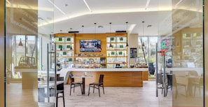 A modern bar area with a TV screen, wooden counter, and seating. - New! Chic Studio with Marina & Intracoastal View (Hallandale Beach)