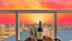 Ein Balkon mit Blick auf eine Stadtlandschaft und ein Gewässer bei Sonnenuntergang.