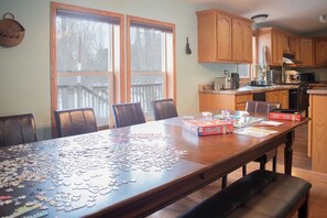 A dining area with a large wooden table, chairs, and a puzzle in progress. - Accessible | Family Friendly | 5 BR | Ripple Lake (Aitken)
