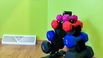 A set of dumbbells on a wooden floor with a green wall and a door in the background.