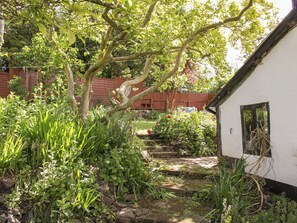 Ein Garten mit einem weißen Gebäude, einem Holzzaun und einem Steinweg.