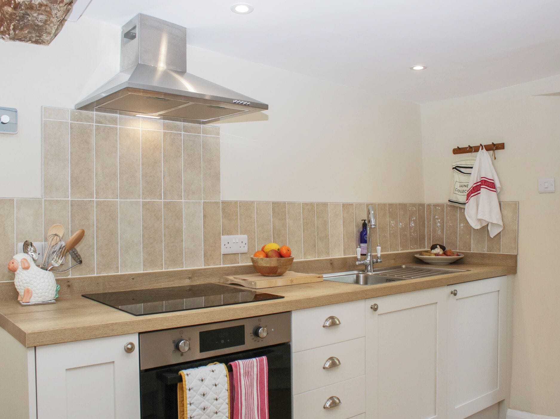 A modern kitchen with a stainless steel range hood, a double sink, and a built-in oven.
