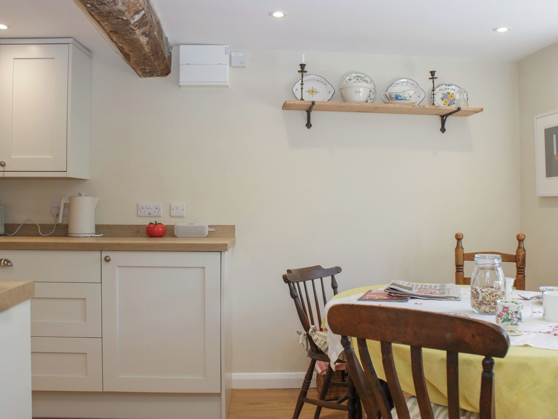 A kitchen with white cabinets, a wooden countertop, a red tomato, and a white kettle.