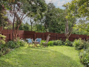 Ein Garten mit Holzzaun, Rasen und zwei Stühlen.