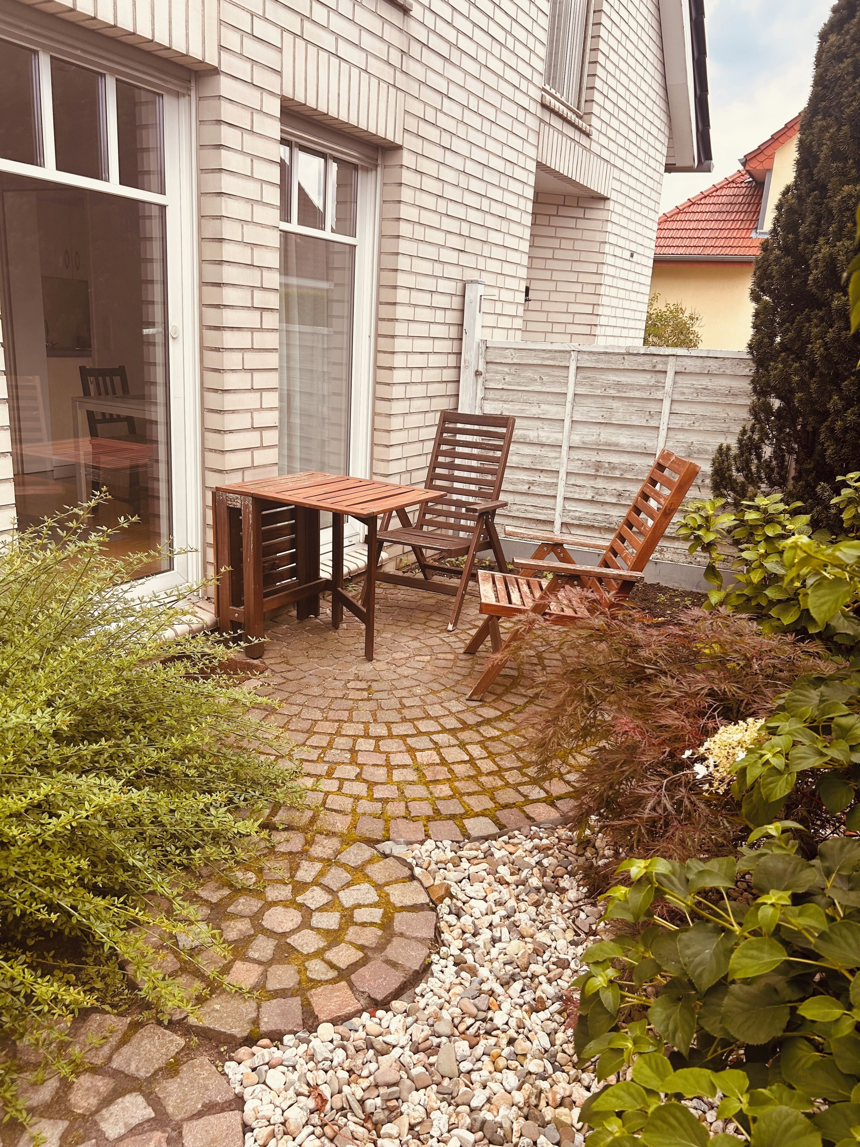 A patio area with a table and chairs, a brick wall, and a wooden fence.