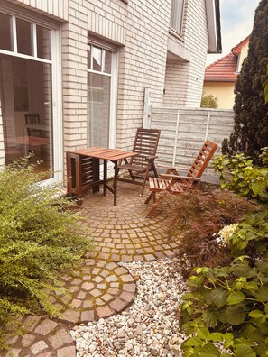 Eine Terrasse mit Tisch und Stühlen, eine Ziegelmauer und ein Holzzaun.
