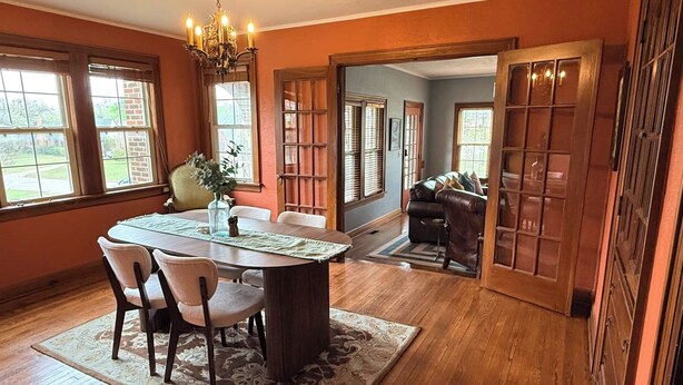 A dining area with a table, chairs, a chandelier, and a view through a doorway. - Hill Street Retreat (Oklahoma City)