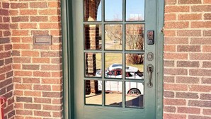 A green door with a US Mail mailbox, a doormat with 'WELCOME' text, and a view of a parked car and trees. - Hill Street Retreat (Oklahoma City)
