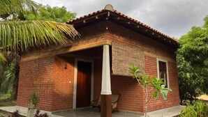 Una casa de ladrillo con techo de tejas, un porche y un pequeño jardín.