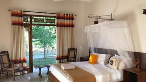 Un dormitorio con cama, una silla, una mesita de noche y una ventana con cortinas.