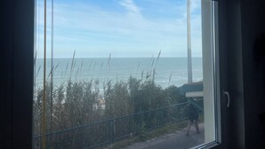 A view through a window with a metal railing, a clear sky, and the ocean. - "Window to the Sea" Spacious and new sea view apartment (Marina di San Vito)