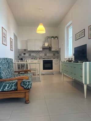 Una cocina moderna con gabinetes blancos, un horno negro y una lámpara colgante.
