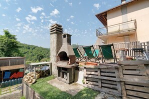 A courtyard with a stone oven, wooden fence, and a building with a balcony.