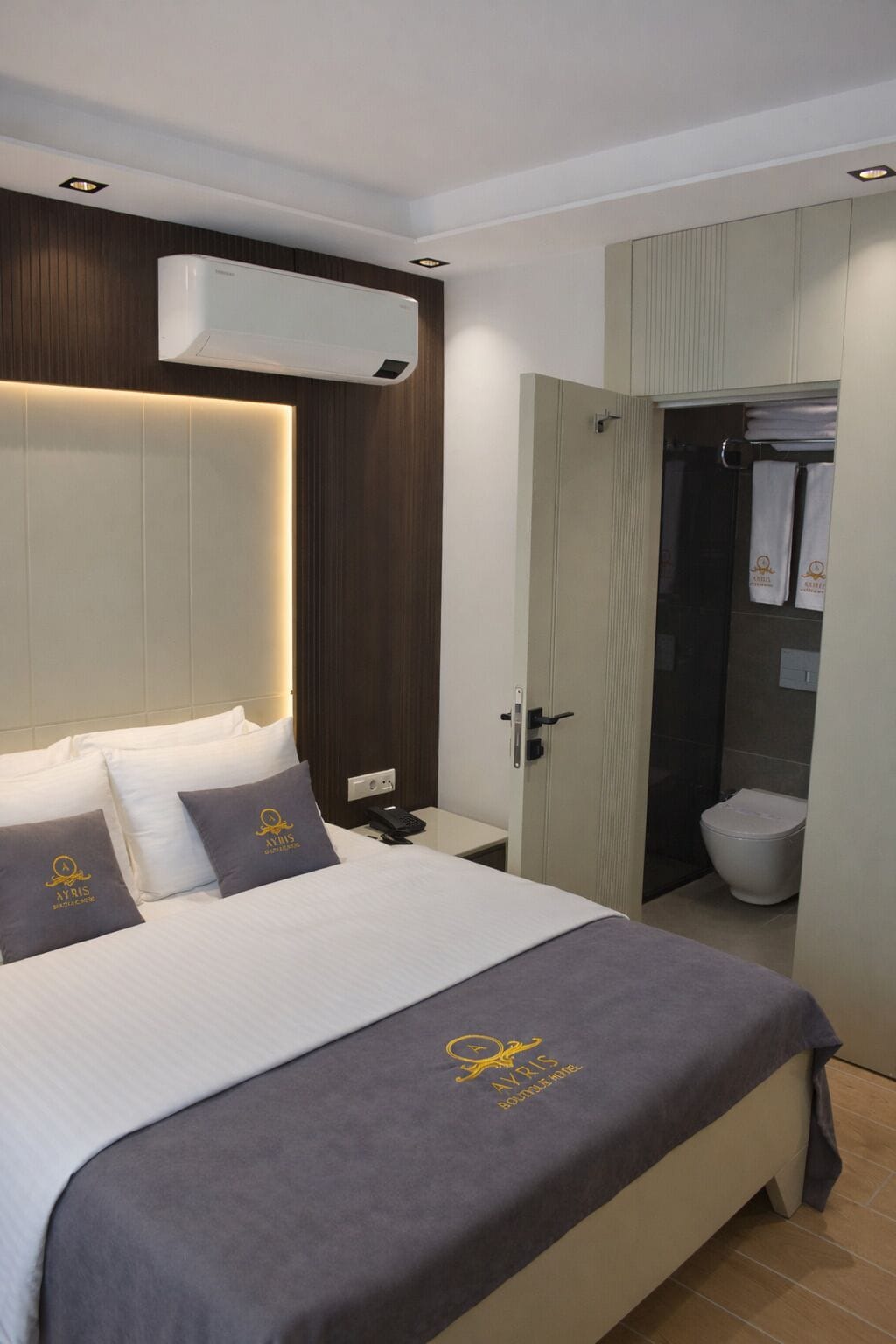 Habitación de hotel con cama, mesita de noche y aire acondicionado.