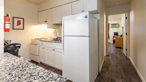 Una cocina compacta con armarios blancos, un refrigerador, una estufa y un microondas.