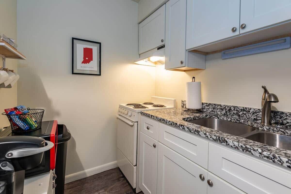 A kitchen with white cabinets, a granite countertop, a stove, and a sink.