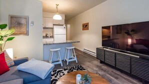 Un espacio habitable compacto con kitchenette, un sofá, una mesa de centro y un televisor.