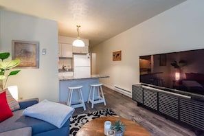 A compact living space with a kitchenette, a sofa, a coffee table, and a TV. - Maple Row Apartment: Perfect for Game Day! (Bloomington)