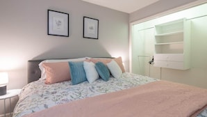 A bedroom with a bed, a nightstand, a dresser, and a window with a shelf. - Blush Bungalow: Cozy Home Near Downtown Bloomington (Bloomington)
