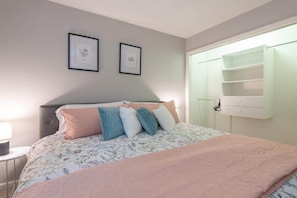 Ein Schlafzimmer mit Bett, Nachttisch, Kommode und Fenster mit Ablage.