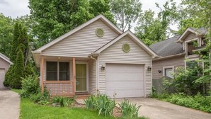 A single-story house with a front porch, a garage, and a small garden area. - Blush Bungalow: Cozy Home Near Downtown Bloomington (Bloomington)