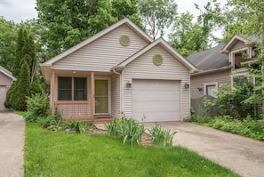 Ein eingeschossiges Haus mit Veranda, Garage und kleinem Garten.