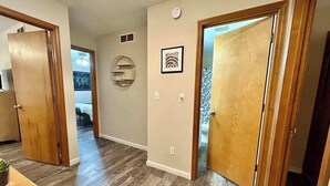 Un couloir doté d’un plancher en bois, d’un élément décoratif rond fixé au mur et d’un tableau encadré.